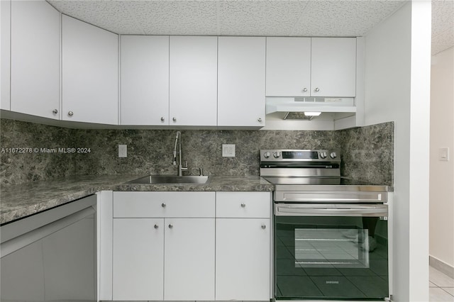 kitchen with electric range, light tile patterned flooring, sink, white cabinetry, and backsplash