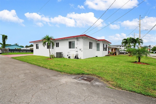 view of side of home with a yard and central AC