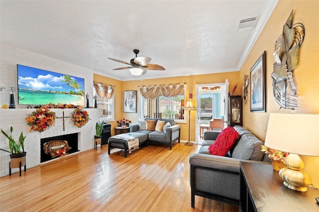 living room featuring crown molding, light wood-style floors, visible vents, and ceiling fan