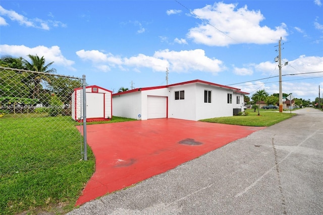 exterior space featuring a front lawn, fence, a shed, stucco siding, and an outbuilding