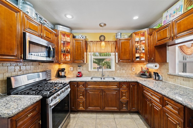 kitchen featuring light stone counters, stainless steel appliances, sink, pendant lighting, and light tile patterned floors