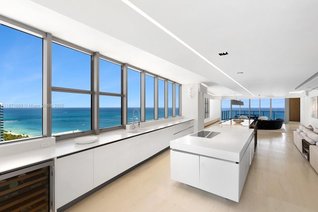 kitchen featuring white cabinetry, a kitchen island, wine cooler, black electric stovetop, and a water view