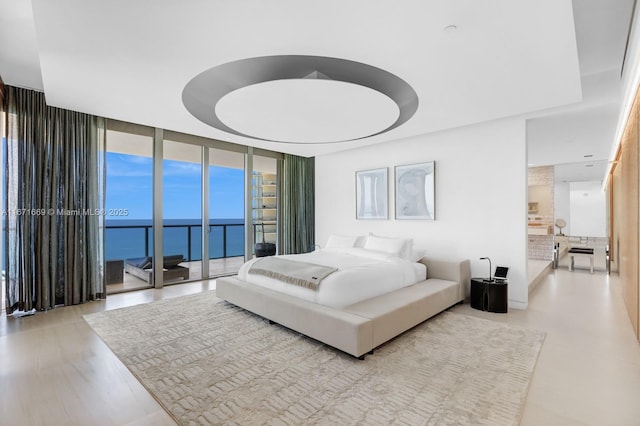 bedroom featuring access to exterior, a water view, and floor to ceiling windows