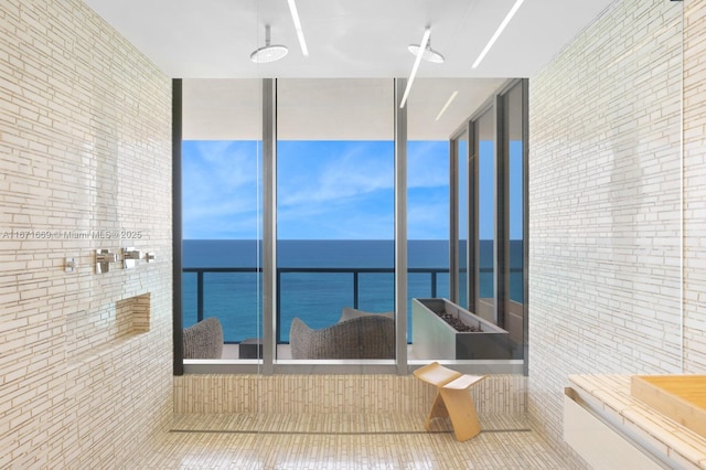 bathroom with tile patterned floors, a water view, and tile walls