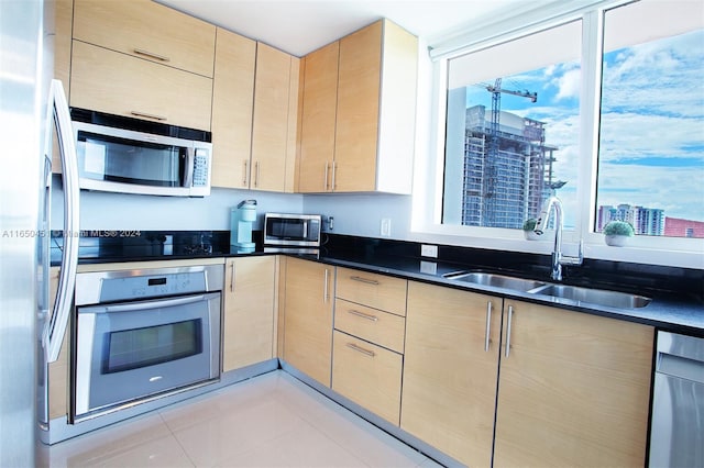 kitchen with appliances with stainless steel finishes, sink, light brown cabinetry, and light tile patterned floors