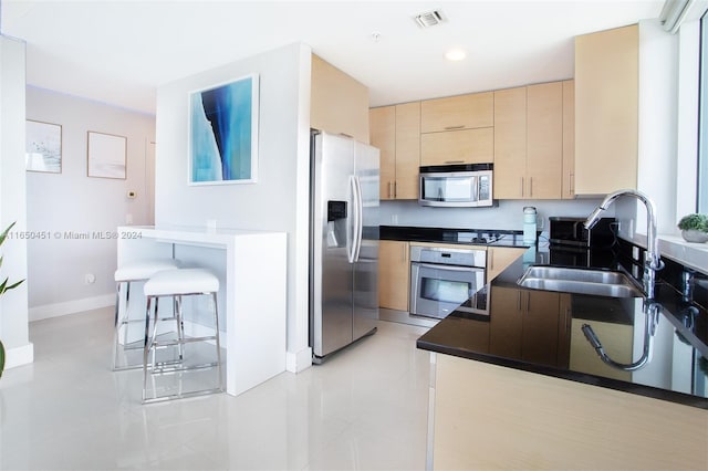 kitchen with light brown cabinetry, appliances with stainless steel finishes, sink, and light tile patterned floors