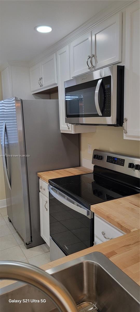 kitchen with white cabinets, stainless steel appliances, and wood counters