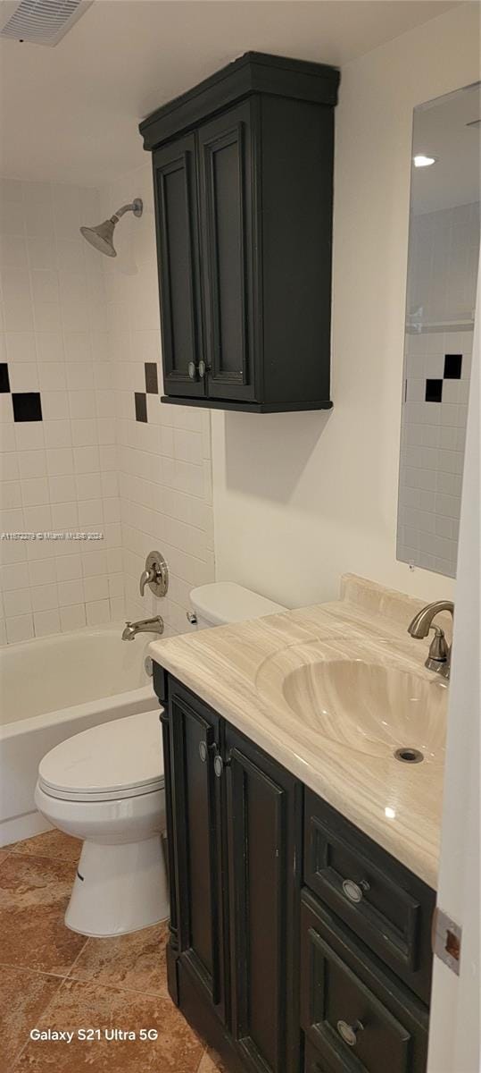 full bathroom with tile patterned floors, tiled shower / bath, vanity, and toilet