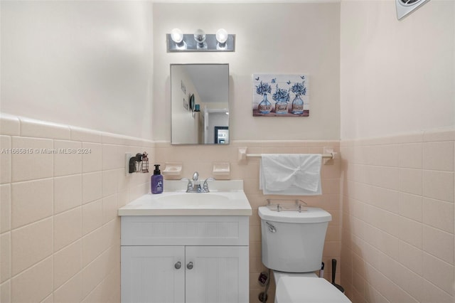 bathroom featuring toilet, vanity, and tile walls