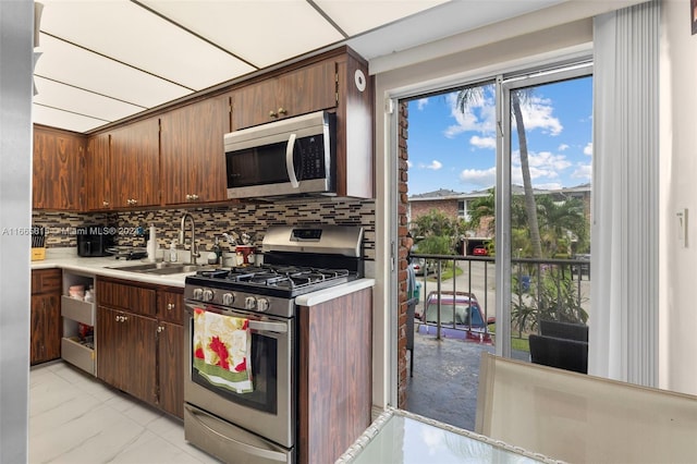 kitchen featuring dark brown cabinets, appliances with stainless steel finishes, backsplash, and sink