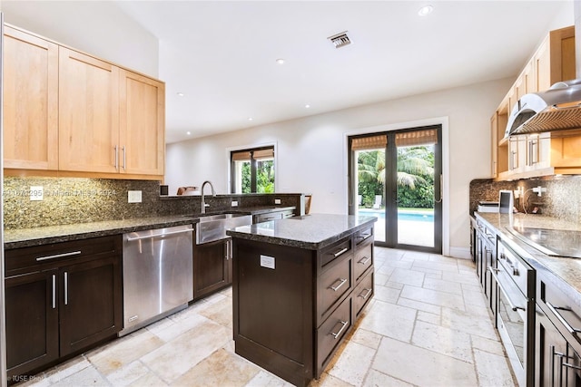 kitchen with sink, backsplash, a center island, stainless steel appliances, and dark stone countertops