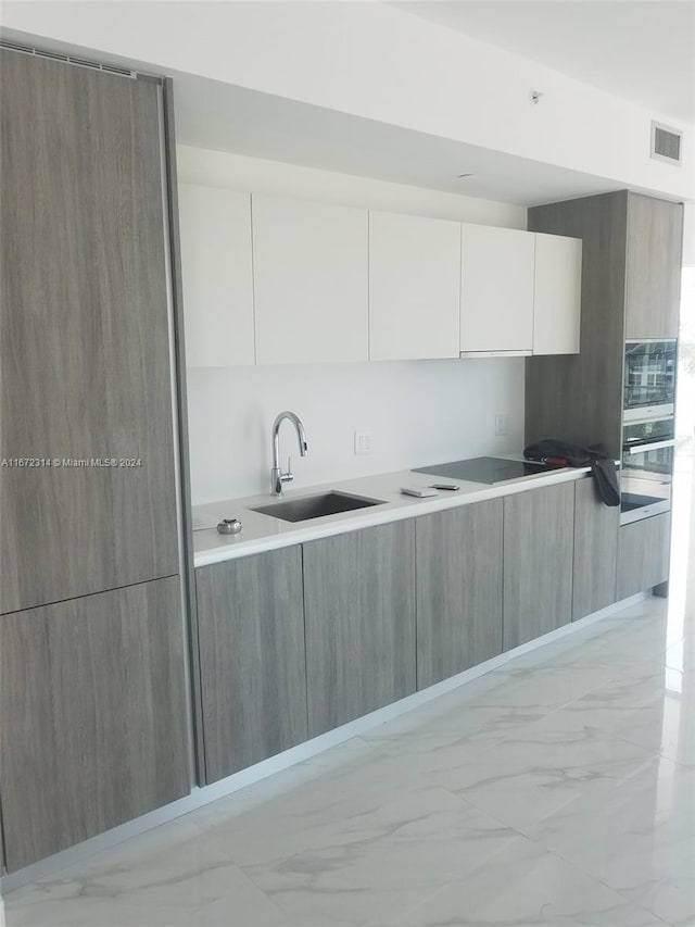 kitchen with white cabinets, stovetop, and sink