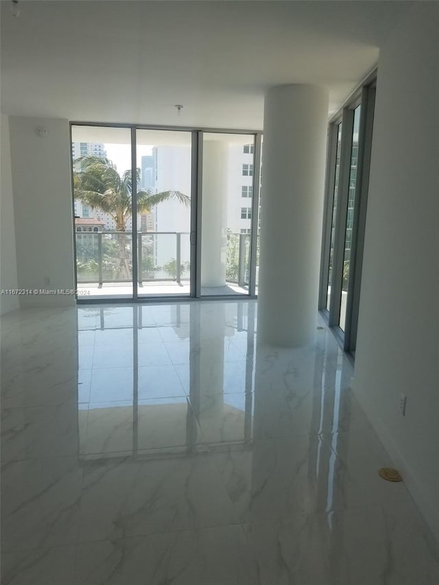 spare room featuring expansive windows and decorative columns