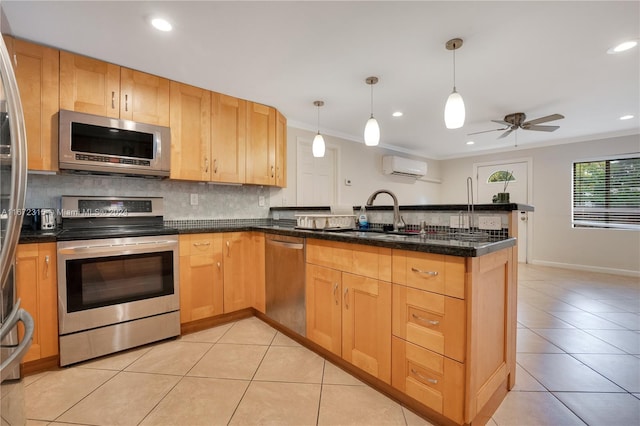 kitchen with sink, appliances with stainless steel finishes, kitchen peninsula, and pendant lighting