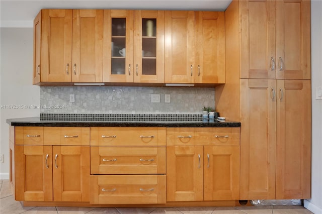 kitchen featuring decorative backsplash, light tile patterned flooring, and dark stone countertops