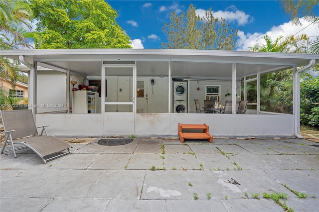 exterior space with stacked washer / dryer, a patio, and a sunroom