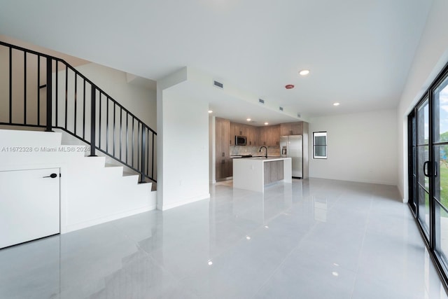 unfurnished living room with light tile patterned flooring and sink