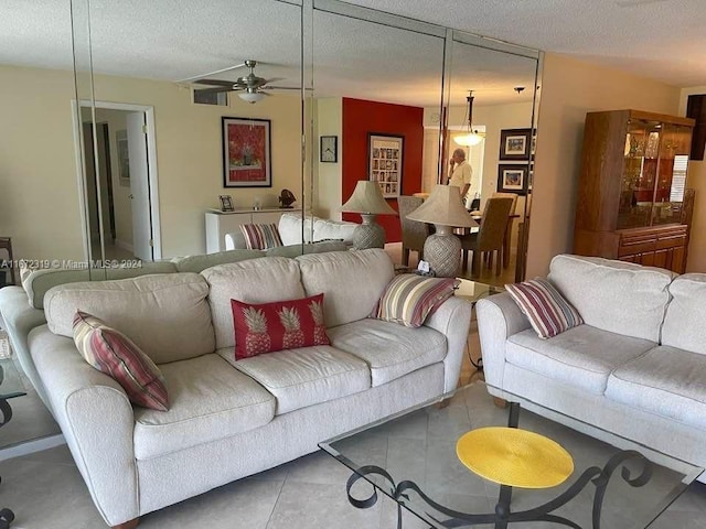 living room with ceiling fan and a textured ceiling