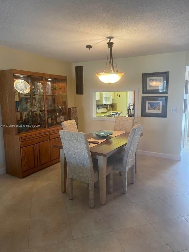 dining space with a textured ceiling and light tile patterned flooring