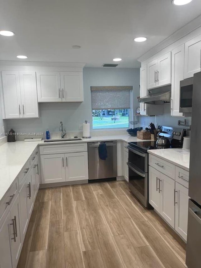 kitchen featuring light wood-type flooring, white cabinetry, sink, and appliances with stainless steel finishes