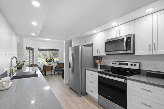 kitchen with white cabinets, stainless steel appliances, light hardwood / wood-style floors, and sink