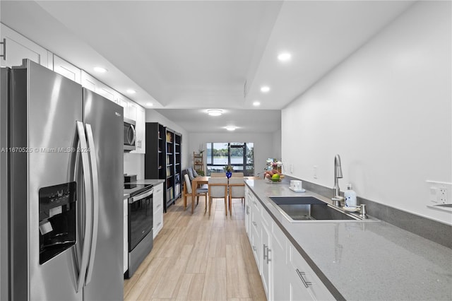 kitchen with sink, white cabinets, light hardwood / wood-style flooring, and appliances with stainless steel finishes