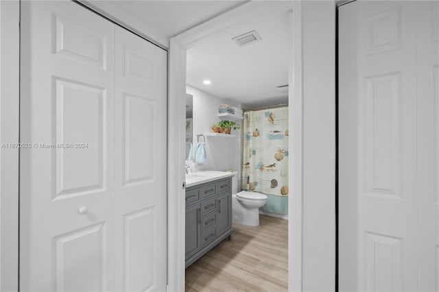 bathroom with a shower with shower curtain, vanity, toilet, and wood-type flooring