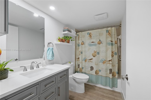 full bathroom with hardwood / wood-style floors, vanity, shower / tub combo with curtain, and toilet