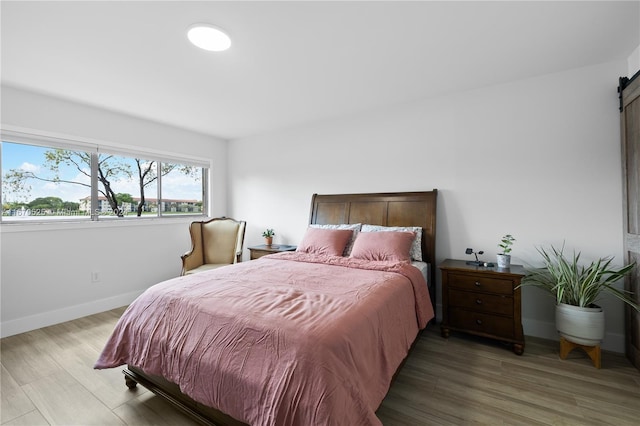 bedroom with a barn door and hardwood / wood-style flooring