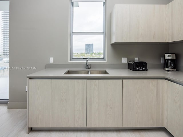 kitchen with light hardwood / wood-style floors, light brown cabinetry, and sink