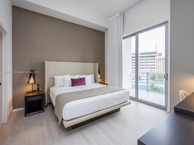 bedroom featuring light wood-type flooring, multiple windows, and access to exterior