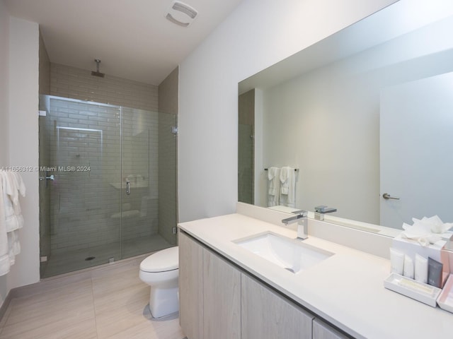 bathroom featuring walk in shower, vanity, tile patterned flooring, and toilet