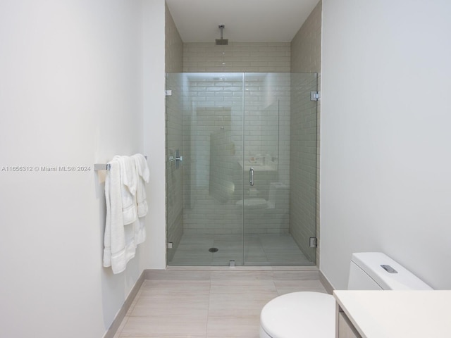 bathroom with tile patterned floors, a shower with door, vanity, and toilet