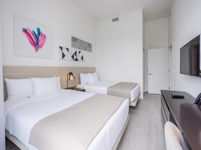 bedroom with wood-type flooring and a towering ceiling