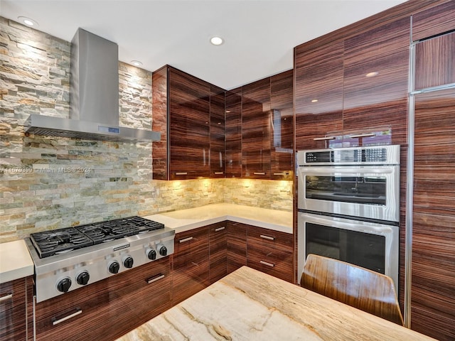 kitchen with wall chimney exhaust hood, backsplash, and stainless steel appliances