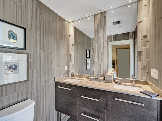 bathroom featuring tile walls, vanity, and toilet