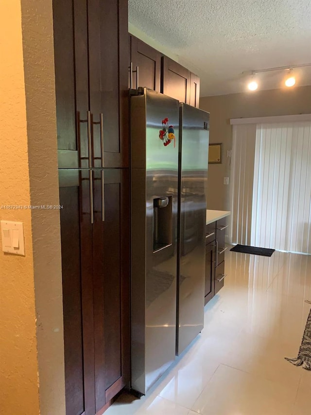 kitchen with a textured ceiling, stainless steel refrigerator with ice dispenser, and dark brown cabinets