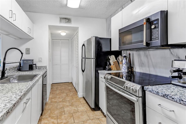 kitchen with appliances with stainless steel finishes, white cabinetry, sink, and a textured ceiling