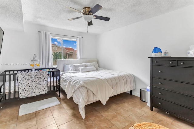 bedroom with ceiling fan, a textured ceiling, and light tile patterned floors