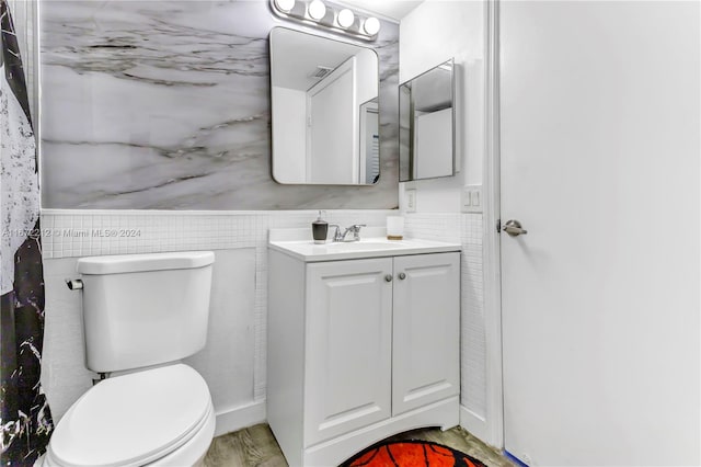 bathroom featuring tile walls, hardwood / wood-style flooring, vanity, and toilet