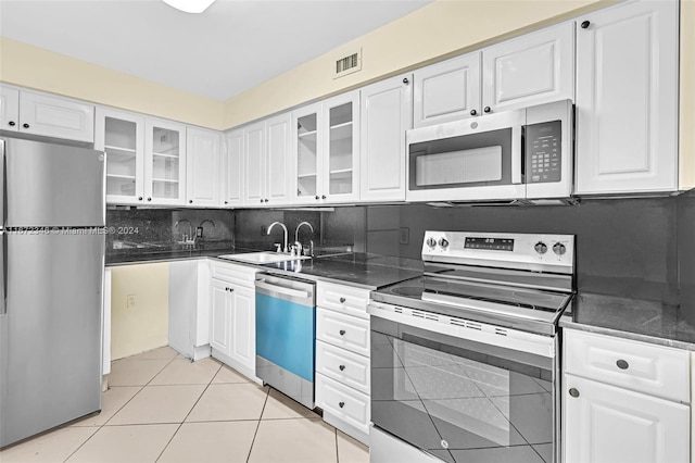 kitchen with stainless steel appliances, light tile patterned flooring, tasteful backsplash, and white cabinetry