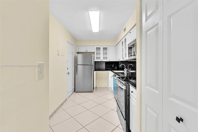 kitchen featuring stainless steel appliances, white cabinets, sink, light tile patterned flooring, and backsplash