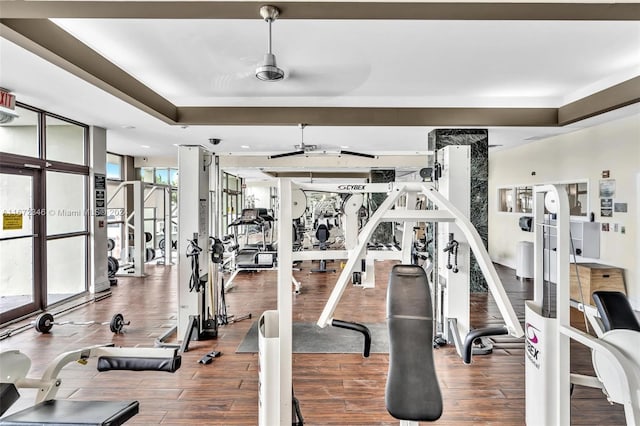 exercise room featuring hardwood / wood-style floors and a raised ceiling