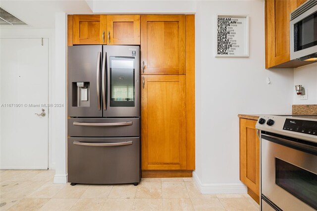 1745 E Hallandale Beach Blvd Unit 1804W, Hallandale Beach, FL 33009 - kitchen with visible vents, appliances with stainless steel finishes, brown cabinets, light tile patterned floors, and baseboards