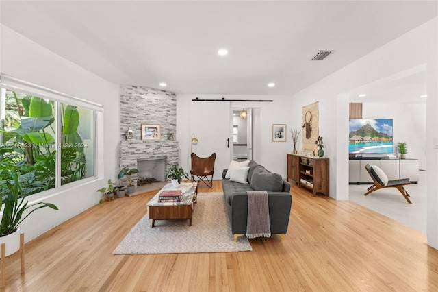 living room featuring a barn door, a fireplace, and light wood-type flooring