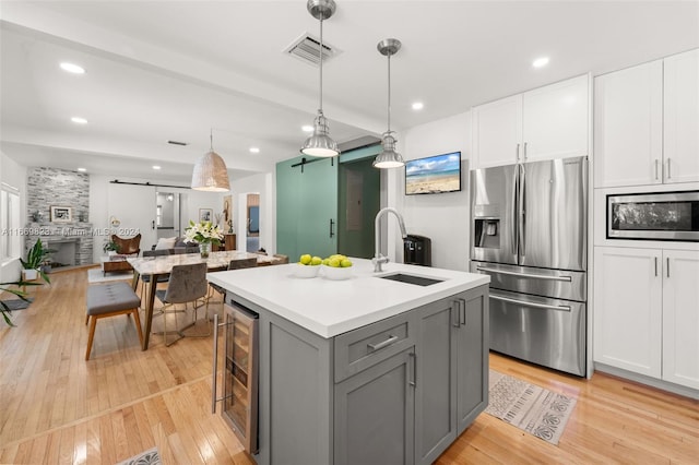 kitchen featuring white cabinetry, gray cabinetry, stainless steel appliances, and light hardwood / wood-style floors