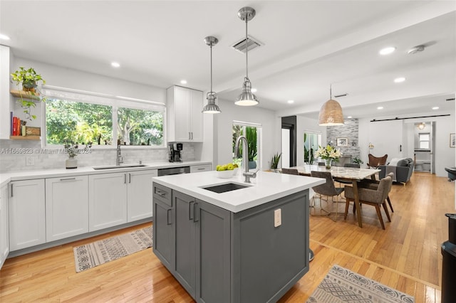 kitchen with sink, pendant lighting, a barn door, and white cabinets