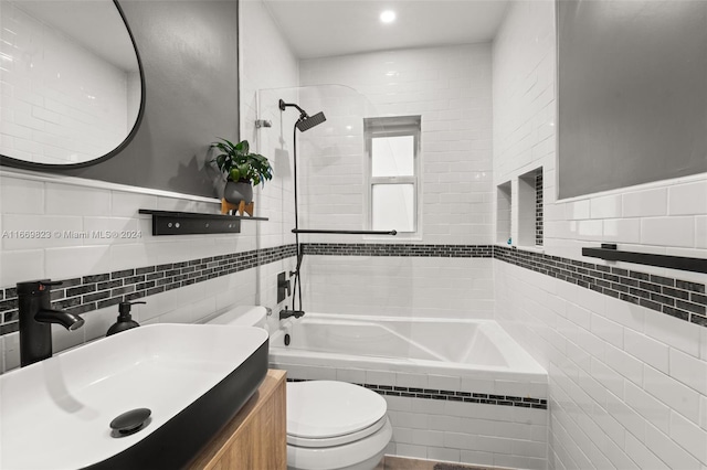 full bathroom with vanity, tiled shower / bath, toilet, and tile walls