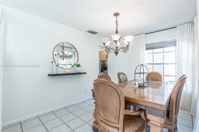 dining area with light tile patterned floors, a textured ceiling, and a chandelier