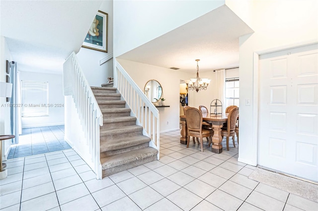 stairway with a chandelier and tile patterned floors